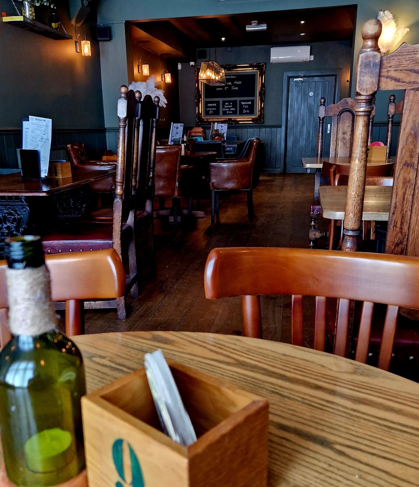 Inside The Mucky Duck: wooden tables, leather armchairs and warm wall lamps against dark green panelling